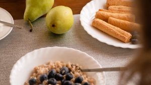 A cozy breakfast scene featuring blueberry oatmeal, pears, and pastries.
